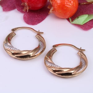 May include: A pair of gold hoop earrings with a twisted design. One earring is gold and the other is two-toned with a silver stripe.