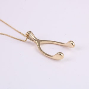 May include: A gold-tone necklace with a wishbone pendant. The pendant is a simple, classic design.