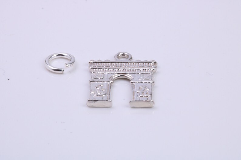 May include: Silver charm in the shape of an archway, with a small jump ring attached.