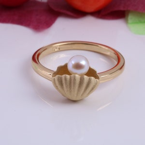May include: A gold ring with a pearl in a seashell design.