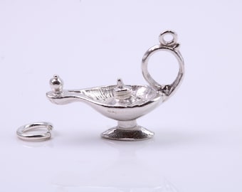 Puede incluir: Un amuleto de plata con forma de lámpara de aceite con un bucle para sujetarlo a un collar o pulsera.