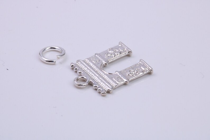May include: Silver charm in the shape of an archway with detailed carvings. The charm has a jump ring attached for easy hanging.