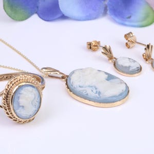 May include: A set of gold jewelry featuring blue cameo pendants. The set includes a ring, a necklace, and a pair of earrings.