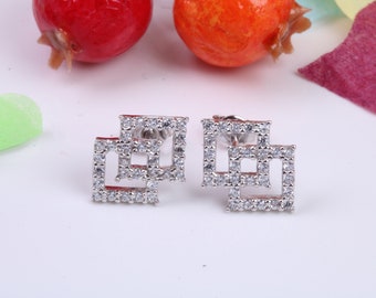 May include: A pair of silver earrings with a geometric design. Each earring features three interlocking squares, each adorned with small, clear cubic zirconia stones.