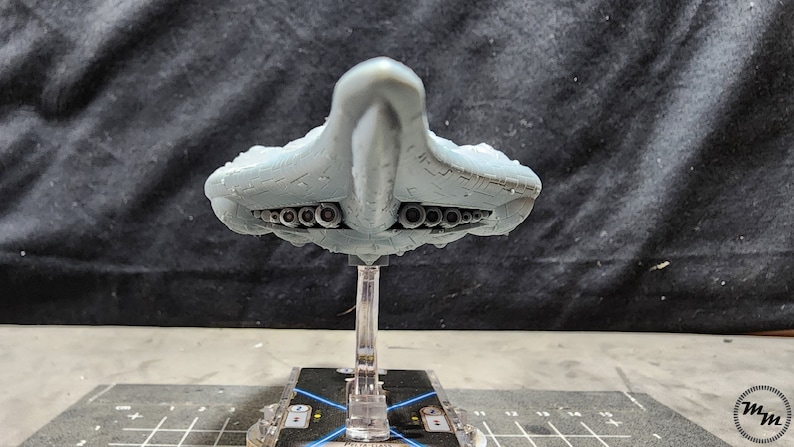 May include: A grey, detailed model of a spaceship with a pointed nose and a row of circular exhaust ports on the underside. The model is mounted on a clear plastic stand.