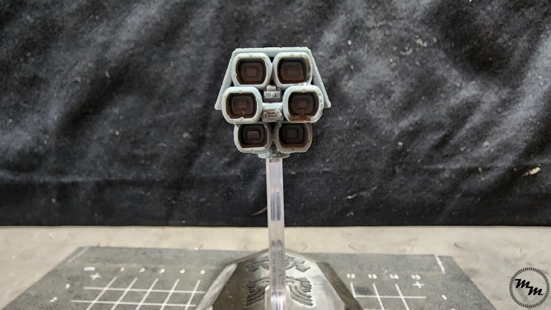 May include: A gray model of a spaceship with a cluster of eight brown exhaust ports on the back. The model is mounted on a clear plastic stand.