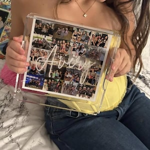 Puede incluir: Una bandeja de acrílico transparente con un collage de fotos en su interior. Las fotos son de un grupo de personas, y la bandeja tiene el nombre "Avery" escrito en blanco.
