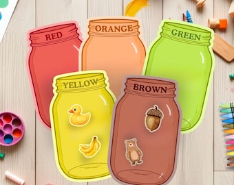 May include: Five colorful mason jar cutouts labeled Red, Orange, Green, Yellow, and Brown. The Yellow jar has a duck and banana sticker. The Brown jar has an acorn and bear sticker. Other art supplies are scattered around.
