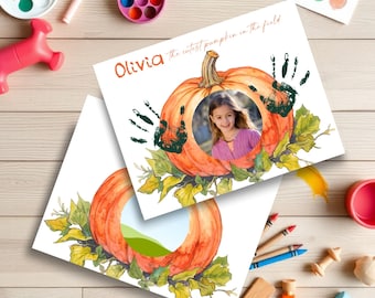 May include: Two white photo prints featuring a watercolor pumpkin design with green leaves. One print has a photo of a girl and green handprints. The text "Olivia the cutest pumpkin in the field" is visible.