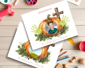 May include: Two white cards with pumpkin and cross designs. One card has a photo of a child inside the pumpkin. The text "jesus picked me" and "the cutest pumpkin in the field" are written on the cards. Green handprints and foliage surround the pumpkin.