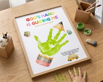 May include: A framed print featuring a green handprint shaped like a pencil with the text GOD'S HAND IS GUIDING ME this is school year and a yellow school bus graphic. The print includes the Bible verse Isaiah 41:13 and small book icons.