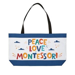 May include: A blue and white tote bag with the text "Peace Love Montessori" in colorful letters. The bag has black handles.
