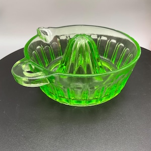 May include: A vintage green glass citrus juicer with a fluted design and two handles.