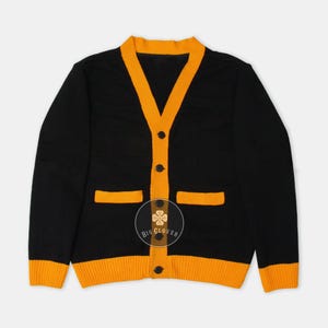 Suéter unisex hecho a mano de punto jacquard en negro y dorado amarillo con letras griegas bordadas para graduación de animadoras de colegio y universidad