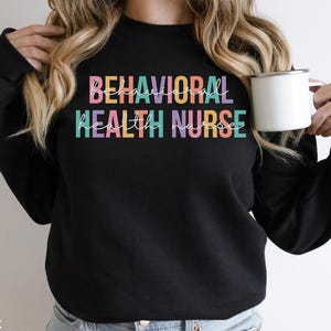 May include: Black sweatshirt with the text "BEHAVIORAL HEALTH NURSE" in rainbow colors.