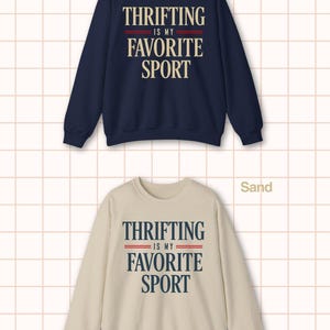 May include: Navy blue and sand-colored sweatshirts. Each sweatshirt features the text "THRIFTING IS MY FAVORITE SPORT" in a bold, vintage-inspired font. The text is in white and navy blue, with red accent lines.