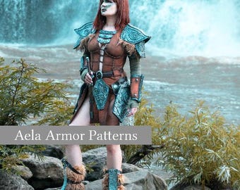 May include: A woman wearing brown and teal fantasy armor stands on a rock near a waterfall. The armor includes shoulder pads, a breastplate, and leg coverings. The text "Aela Armor Patterns" is displayed on the image.