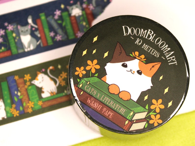 May include: A roll of washi tape featuring a calico cat with orange, white and brown fur. The cat is sitting on a stack of books with the text "Cats x Literature Washi Tape" and is surrounded by yellow flowers and sparkling stars. The background is dark green and the text "Doombloomart ~ 10 metres ~" is printed on the top right corner.
