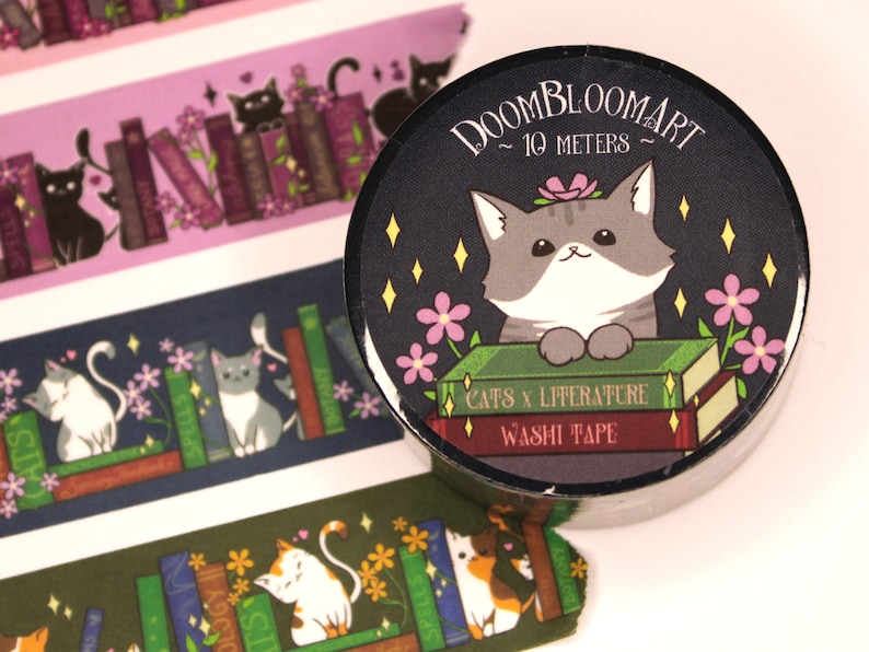 May include: A black and white cat with pink flowers sits on a stack of books with the text "Doombloomart ~ 10 meters ~ Cats x Literature Washi Tape" on a black background.