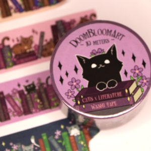 May include: Purple washi tape featuring a black cat perched on top of two books. The tape has a purple background with white flowers and black diamonds. The text on the tape reads "DOOMBLOOMART - 10 METERS - CATS & LITERATURE WASHI TAPE".