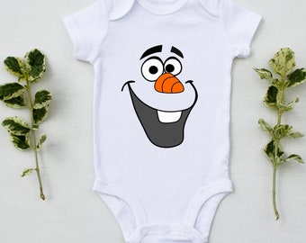 Puede incluir: Un body blanco para bebé con una imagen de dibujos animados de Olaf de la película Frozen. La cara de Olaf está impresa en el body, con su nariz de zanahoria característica y su gran sonrisa.