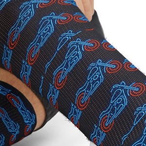 May include: Black socks with a repeating pattern of blue and red motorcycle illustrations. The socks are being pulled up, showcasing the design. The motorcycle design is a neon style.