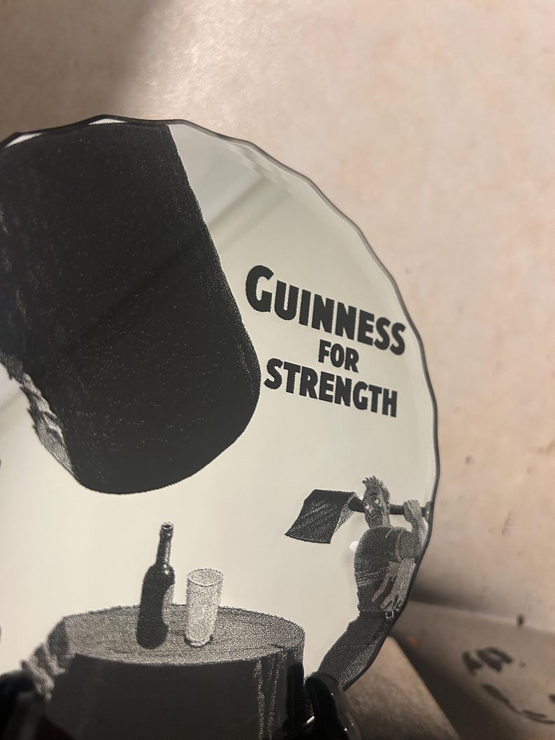 May include: A white and black Guinness advertisement featuring the text "Guinness for Strength." The image shows a man swinging an axe, a bottle, and a glass on a table.