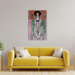 May include: A rectangular wall art print featuring a vertical painting of a figure wearing a large black hat and a long, light-colored patterned garment. The background consists of horizontal bands of red, green, and purple with floral motifs.
