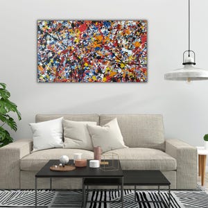 May include: A rectangular canvas wall art piece featuring a dense, multi-coloured paint splatter design. The composition includes vibrant splashes of red, blue, yellow, orange, and black paint layered across the surface in an abstract, chaotic pattern.