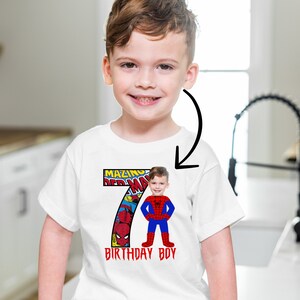 Op de afbeelding: Wit T-shirt met een rood en blauw nummer 7 met een stripboekontwerp en de woorden "Amazing Spiderman" en "Birthday Boy". Het gezicht van een kind is over het Spiderman-personage gelegd.