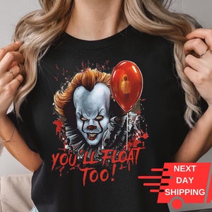 May include: Black t-shirt with a graphic of Pennywise the clown from the movie "IT" holding a red balloon. The text "You'll Float Too!" is printed below the graphic.