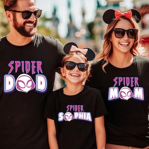May include: A family of three wearing black t-shirts with a spider graphic and the text "Spider Dad", "Spider Mom", and "Spider Sophia".