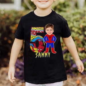 Op de afbeelding: Zwart T-shirt met een rode en blauwe Spiderman-afbeelding en de tekst "AMAZIN' SPIDER" en "SAMMY".