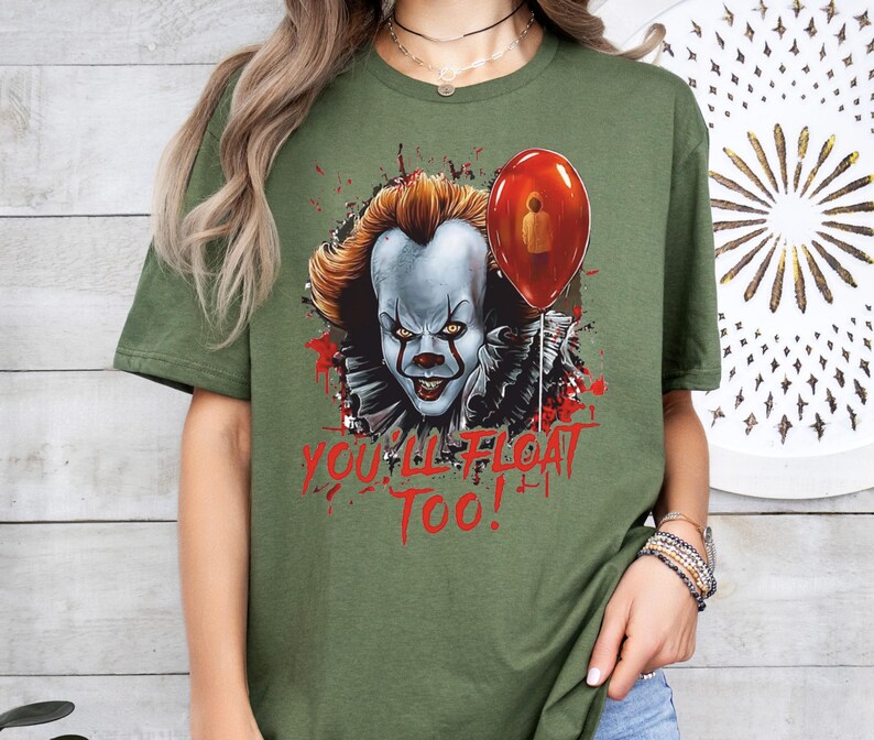 May include: Green t-shirt with a graphic of Pennywise the clown from the movie "IT" with a red balloon. The text "You'll Float Too!" is printed below the graphic.