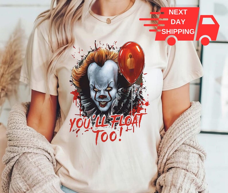 May include: A white t-shirt with a graphic of Pennywise the clown from the movie "IT". The graphic shows Pennywise with a red balloon and the text "You'll Float Too!"