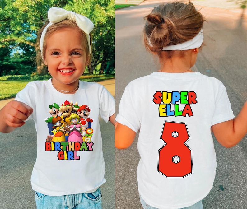 May include: White t-shirt with a colorful graphic of Mario characters and the text "Birthday Girl". The back of the shirt has the text "Super Ella" and the number "8" in red.