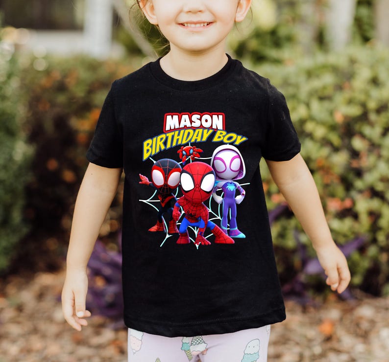 Puede incluir: Camiseta negra con un gr&aacute;fico de tres personajes de Spider-Man de dibujos animados. El texto "MASON BIRTHDAY BOY" est&aacute; impreso en amarillo en la camiseta.