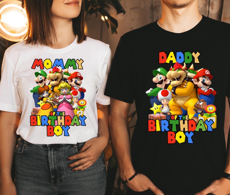 May include: White and black t-shirts with a graphic of Mario characters. The white shirt says "Mommy of the Birthday Boy" and the black shirt says "Daddy of the Birthday Boy".