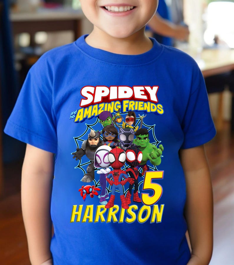 Puede incluir: Camiseta azul con el texto "Spidey and his Amazing Friends" y un gr&aacute;fico de los personajes. El n&uacute;mero "5" y el nombre "Harrison" son de color amarillo. La camiseta est&aacute; hecha de un material suave y es adecuada para ni&ntilde;os.