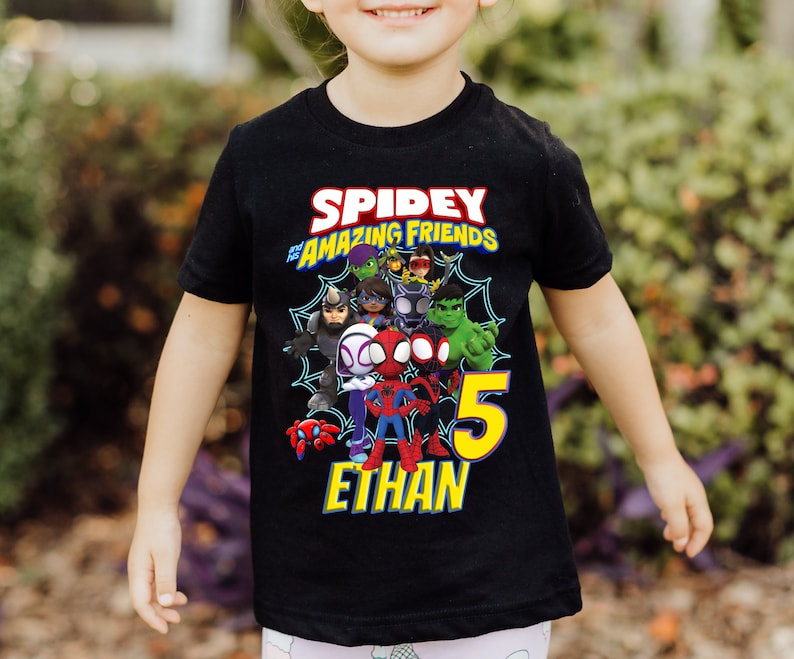 Puede incluir: Camiseta negra con el texto "Spidey and His Amazing Friends" y un gr&aacute;fico de los personajes. El n&uacute;mero "5" es amarillo, con el nombre "Ethan" debajo.