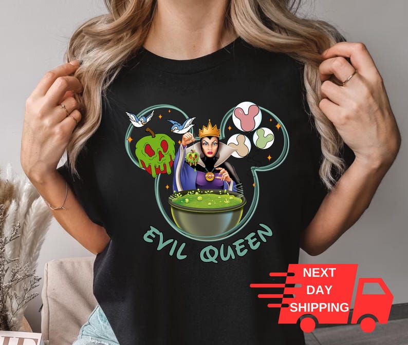 May include: Black t-shirt featuring a graphic of the Evil Queen from Snow White holding a cauldron. The graphic is in the shape of Mickey Mouse's head with a green apple and birds. The text "Evil Queen" is below the graphic.