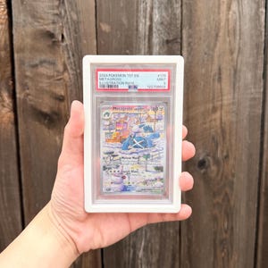 May include: A 2024 Pokemon Metagross Illustration Rare trading card, graded Mint 9 by PSA, encased in a white protective plastic slab. The card features a snowy landscape illustration with the character Metagross, Meteor Mash text, and 180 HP.