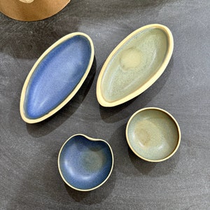 Op de afbeelding: Vier keramische schalen in verschillende vormen en maten. De schalen zijn geglazuurd in tinten blauw en groen.