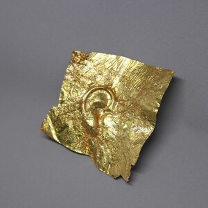 May include: A gold-leaf ear sculpture, a unique and abstract piece of art.