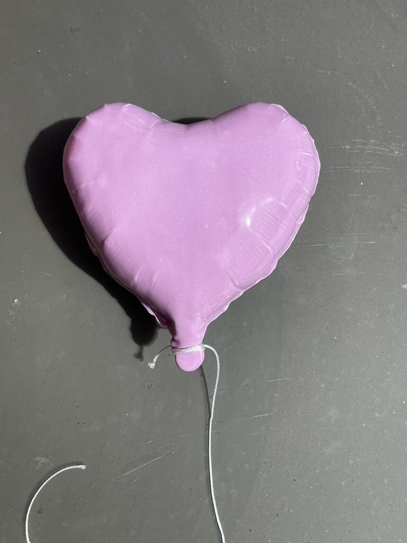 Op de afbeelding: Een paarse hartvormige ballon met een wit touwtje.