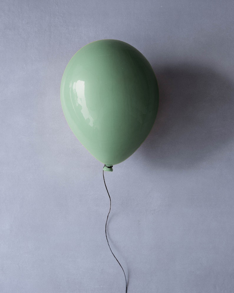 May include: A single, light green balloon with a black string hanging down.