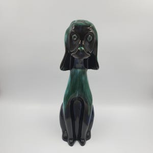 May include: A ceramic dog ornament with a glossy finish. The dog is mainly dark blue and green, in a seated pose with large eyes. The figurine has a sleek, modern design, suitable for home decor, and is a decorative item.