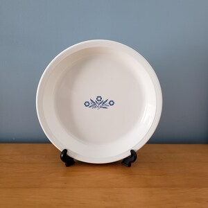 May include: White pie plate with a blue floral design. The plate is on a wooden surface.