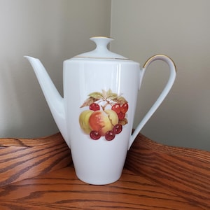 May include: White porcelain coffee pot with a gold trim and a fruit design featuring peaches and cherries.