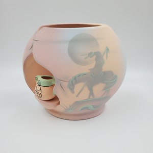 May include: A ceramic pot with a painted scene of a Native American on horseback riding into the sunset. The pot has a small, separate ceramic pot attached to the side.